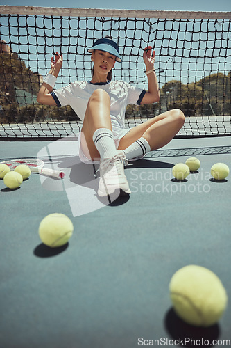 Image of Relax, portrait and tennis woman at net on exercise, fitness and court break at sports ground. Training, workout and cardio of professional athlete club girl resting on floor with tennis balls.