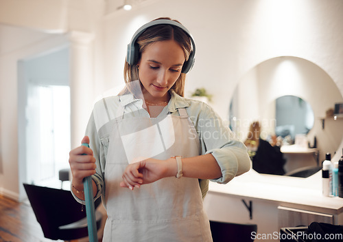 Image of Watch, headphones and woman cleaning salon while streaming music, podcast or radio. Break, cleaner and female from Canada sweeping workplace, looking at time and listening to audio, song or album.