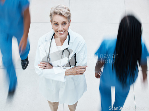 Image of Portrait, happy and doctor in busy hospital standing with crossed arms after consultation. Happiness, medicine and senior healthcare professional with stethoscope working in medical clinic in Canada.