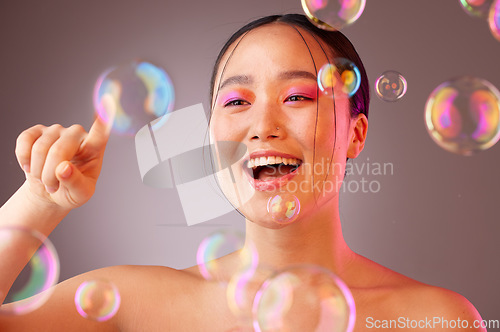 Image of Beauty, bubbles and Asian woman with bright eyeshadow isolated on a studio background. Fun, glamour and colourful cosmetics with a beautiful Chinese woman popping bubbles for a healthy, fresh skin