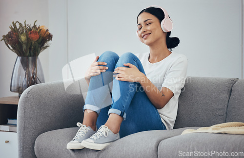 Image of Relax, headphones and woman on sofa in home living room streaming music, podcast or radio. Happy, smile and carefree female from Canada enjoying listening to audio, playlist or favorite song in house