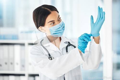 Image of Healthcare, covid and a doctor putting gloves on hands, woman ready for check up examination or surgery in hospital or clinic. Safety, protection and lady medical worker with surgical face mask.