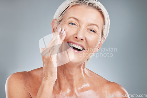 Image of Senior woman, beauty and smile for skincare, moisturizer or cosmetic treatment against a grey studio background. Happy elderly female smiling with teeth in satisfaction for perfect facial skin cream