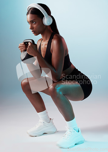 Image of Woman, kettle bell or headphones in training on studio background for exercise, workout or health. Personal trainer, fitness model or sports person squatting with weights, music or motivation podcast