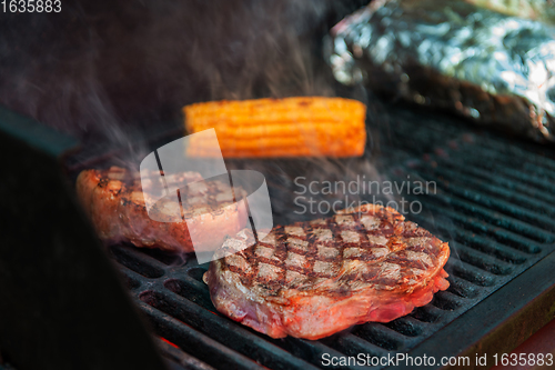 Image of Beef steaks on the grill with flames