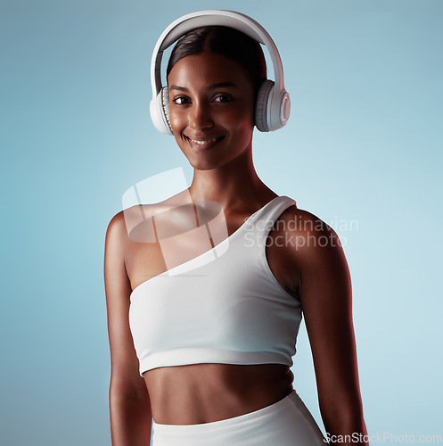 Image of Radio, smile and woman with headphones for music, podcast or motivation during exercise against a blue mockup studio background. Audio, happy and Indian girl training for fitness, energy and cardio