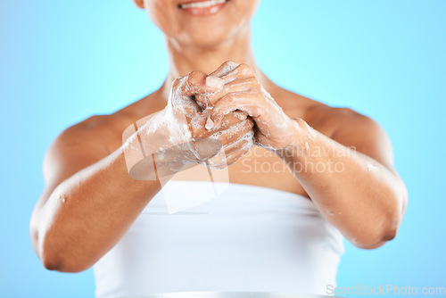 Image of Hands, cleaning and woman washing hands in studio for health, hygiene and safety from bacteria against blue background. Hand, wellness and germ prevention by model with soap, bubble and foam product