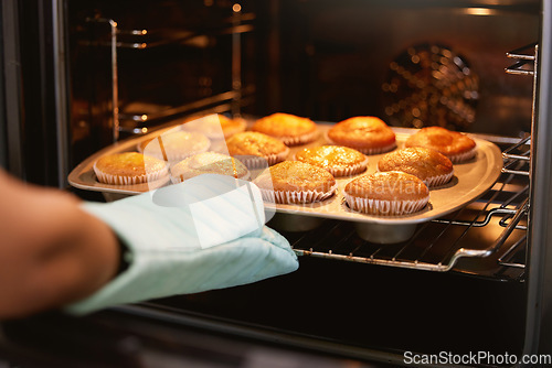 Image of Hand, oven and muffins in baking, food or cooking sweet delicious cakes on a tray at home in the kitchen. Hands of baker taking hot muffin baked meal, treat or delight in pastry making at the house