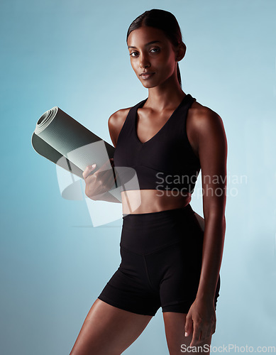 Image of Woman, yoga mat or fitness on blue background in studio for relax workout, training or pilates exercise for mental health or wellness. Portrait, model or yogi with calm, zen or holistic peace mindset