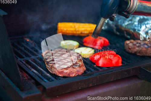 Image of Beef steaks on the grill with flames