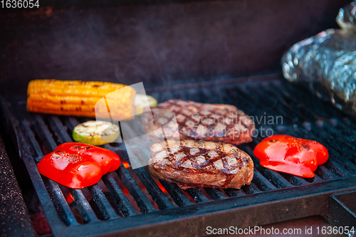 Image of Beef steaks on the grill with flames