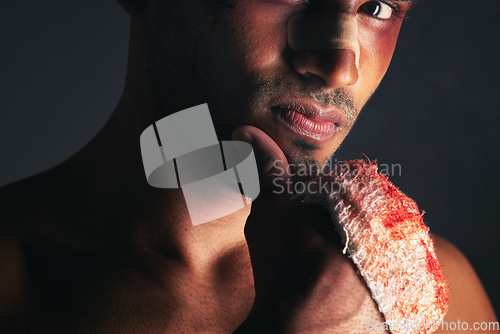 Image of Fight, blood and portrait of man with bruise on eye, face and bloody bandages on hand. Violence, boxing and young male boxer with injury, wounds and hurt from mma sport on black background in studio
