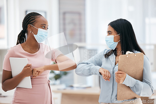 Image of Covid, greeting and teamwork with a business woman and colleague in business working together in their office. Collaboration, diversity and mask with an employee team during the corona virus pandemic