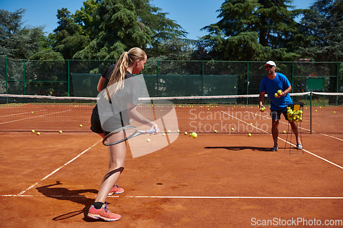 Image of A professional tennis player and her coach training on a sunny day at the tennis court. Training and preparation of a professional tennis player