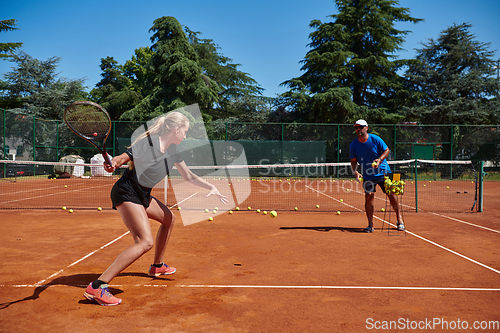 Image of A professional tennis player and her coach training on a sunny day at the tennis court. Training and preparation of a professional tennis player