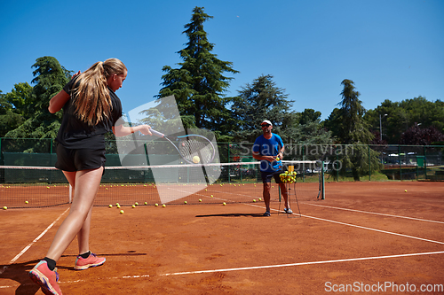 Image of A professional tennis player and her coach training on a sunny day at the tennis court. Training and preparation of a professional tennis player