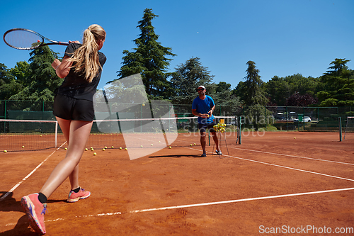 Image of A professional tennis player and her coach training on a sunny day at the tennis court. Training and preparation of a professional tennis player