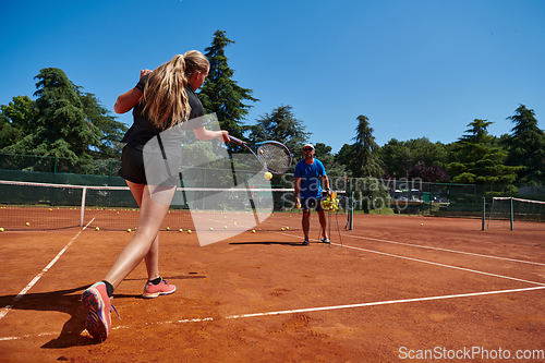 Image of A professional tennis player and her coach training on a sunny day at the tennis court. Training and preparation of a professional tennis player