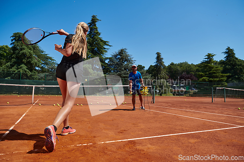 Image of A professional tennis player and her coach training on a sunny day at the tennis court. Training and preparation of a professional tennis player