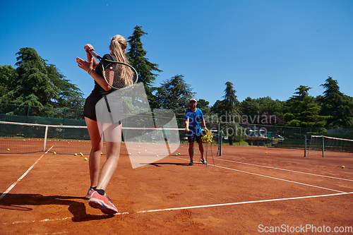 Image of A professional tennis player and her coach training on a sunny day at the tennis court. Training and preparation of a professional tennis player