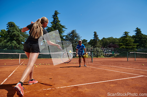 Image of A professional tennis player and her coach training on a sunny day at the tennis court. Training and preparation of a professional tennis player