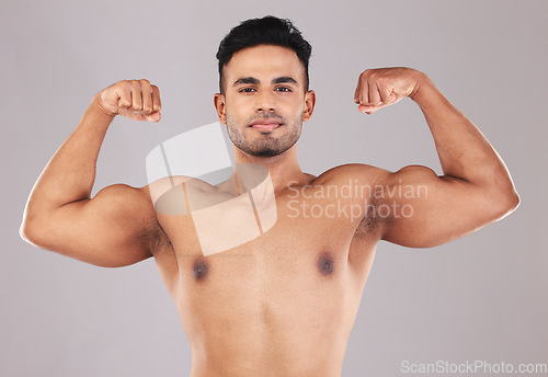 Image of Fitness, portrait and man flexing muscle on gray studio background. Sports, wellness and proud Indian body builder showing biceps, power and arm strength during training, exercise or body workout.