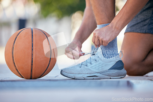 Image of Basketball, sports and shoes with a man athlete tying his laces before a game on an outdoor court. Fitness, exercise and sport with a male basketball player fastening his shoelaces for a match