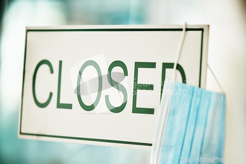 Image of Closed sign, business and covid crisis background at store, shop of company during compliance, lockdown and bankruptcy. Office window with covid 19 ppe mask and information notice during lockdown