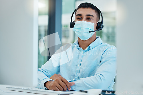 Image of Call center, consultant and covid face mask at desk of telemarketing, CRM and customer support agent at office for help and advice. Male with headset for contact us service on website during covid 19