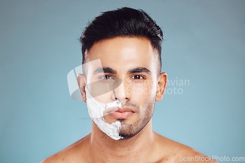 Image of Shaving cream, face and portrait of man in a studio to shave his beard with foam or creme. Beauty, skincare and model from Puerto Rico grooming or cleaning his facial hair isolated by blue background