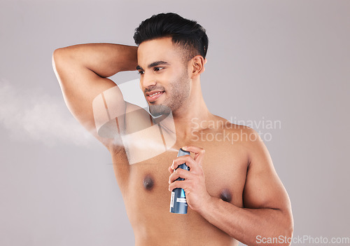 Image of Deodorant, armpit and man spraying in studio for hygiene, wellness and self care. Spray, clean and young model from Colombia with fragrance with a fresh scent for grooming isolated by gray background