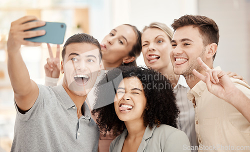 Image of Phone, selfie and work friends with funny faces at team building event or meeting in office. Comic, diversity and goofy business people in collaboration having fun and taking picture in the workplace