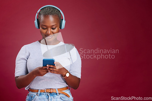 Image of Smartphone, headphone and black woman in studio mock up listening, scroll and typing on music subscription streaming service. African girl using phone audio app on red mockup marketing or advertising