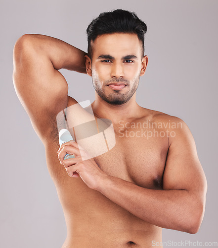 Image of Deodorant, health and man cleaning armpit against a grey studio background. Wellness, care and portrait of a young model with an underarm product for grooming, clean skin and care for body hygiene