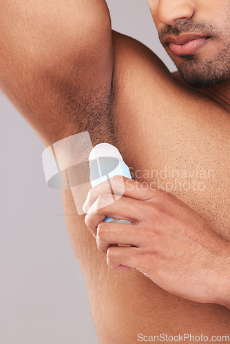 Image of Deodorant, health and man cleaning armpit for wellness, skin and care for body against a grey studio background. Grooming, hygiene and underarm of a person with a product to clean and stop sweat