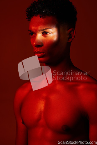 Image of Red, light and body, beauty and man isolated on studio background. Neon light, serious facial expression and male model from Brazil thinking, lost in thought or focus on fitness, health and wellness.