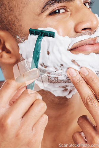 Image of Shaver, foam and man shaving his beard for hygiene, health and smooth skin in a studio. Razor, clean and handsome guy from India grooming his facial hair for dermatology wellness or a face treatment.