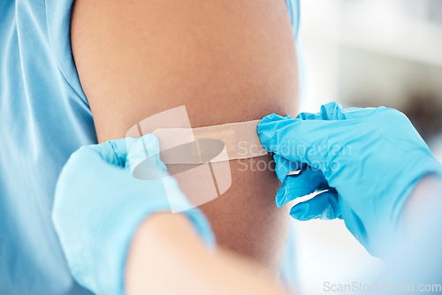 Image of Bandaid, vaccine and arm of patient at the doctor for healthcare, medical attention and consultation with covid. Hands of a hospital nurse with a plaster for an injury, virus or safety while sick