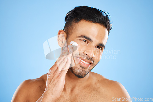 Image of Man, beauty and skincare with smile for moisturizer, cream or facial treatment against a blue studio background. Happy male smiling in satisfaction for skin cosmetics, creme and care for hygiene