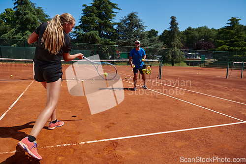 Image of A professional tennis player and her coach training on a sunny day at the tennis court. Training and preparation of a professional tennis player