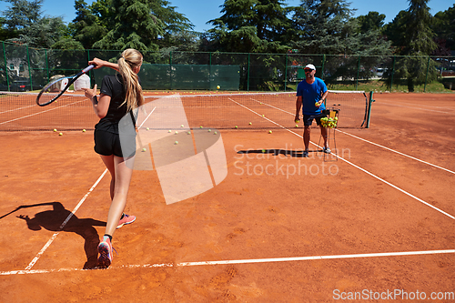 Image of A professional tennis player and her coach training on a sunny day at the tennis court. Training and preparation of a professional tennis player