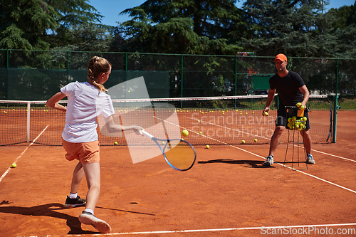 Image of A professional tennis player and her coach training on a sunny day at the tennis court. Training and preparation of a professional tennis player