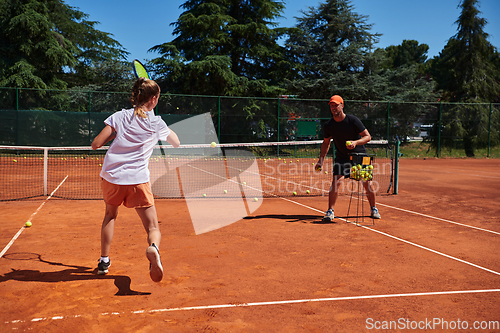 Image of A professional tennis player and her coach training on a sunny day at the tennis court. Training and preparation of a professional tennis player