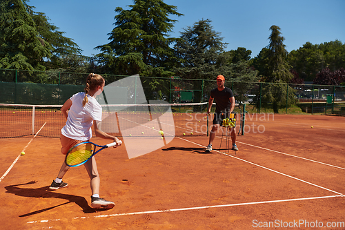 Image of A professional tennis player and her coach training on a sunny day at the tennis court. Training and preparation of a professional tennis player