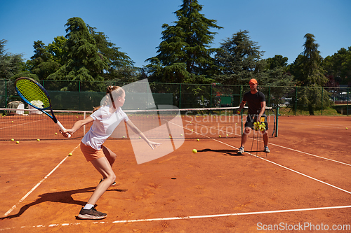 Image of A professional tennis player and her coach training on a sunny day at the tennis court. Training and preparation of a professional tennis player