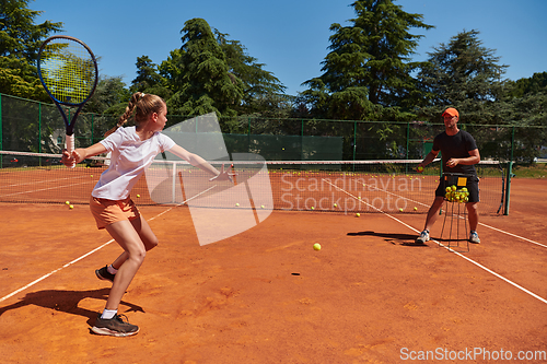 Image of A professional tennis player and her coach training on a sunny day at the tennis court. Training and preparation of a professional tennis player