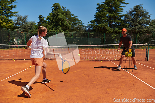 Image of A professional tennis player and her coach training on a sunny day at the tennis court. Training and preparation of a professional tennis player