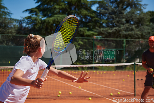 Image of A professional tennis player and her coach training on a sunny day at the tennis court. Training and preparation of a professional tennis player