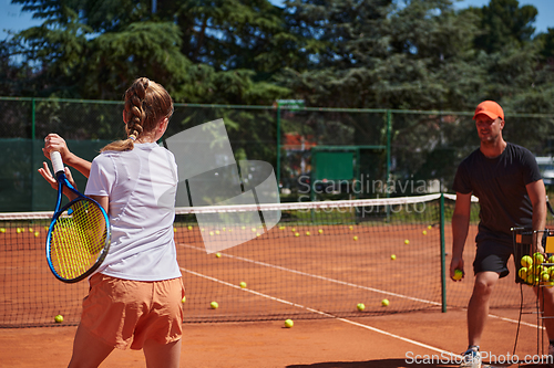 Image of A professional tennis player and her coach training on a sunny day at the tennis court. Training and preparation of a professional tennis player