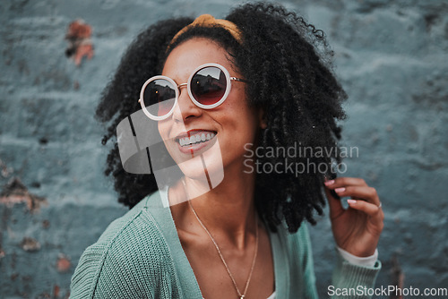 Image of Black woman, fashion and smile with stylish glasses for summer travel against an urban wall background. Happy African American female smiling in satisfaction for fun funky style in the outdoors